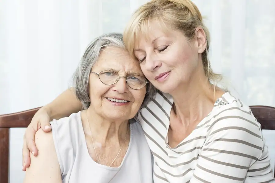 Home Health Aides in Massachusetts | CareLink Home health aide sitting close to a smiling older woman at home, offering companionship and daily support